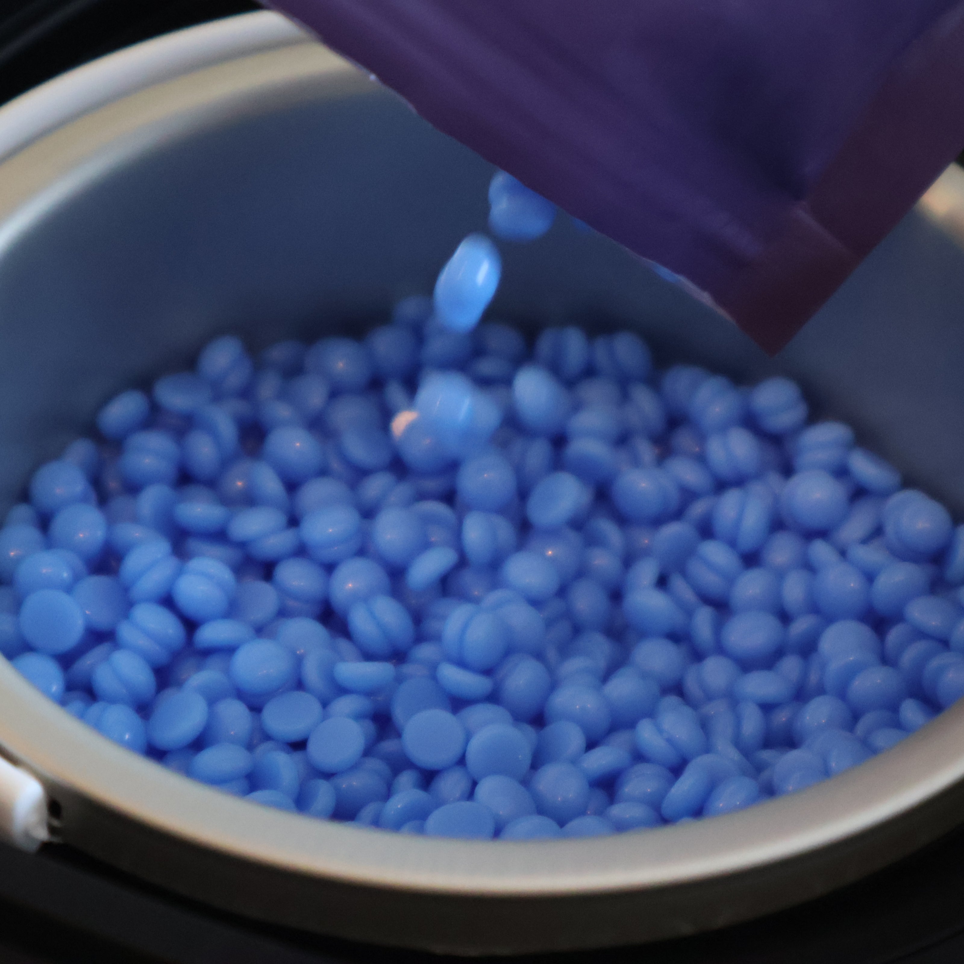 Pouring Lumixsilva hard wax beads into wax warmer for at-home hair removal