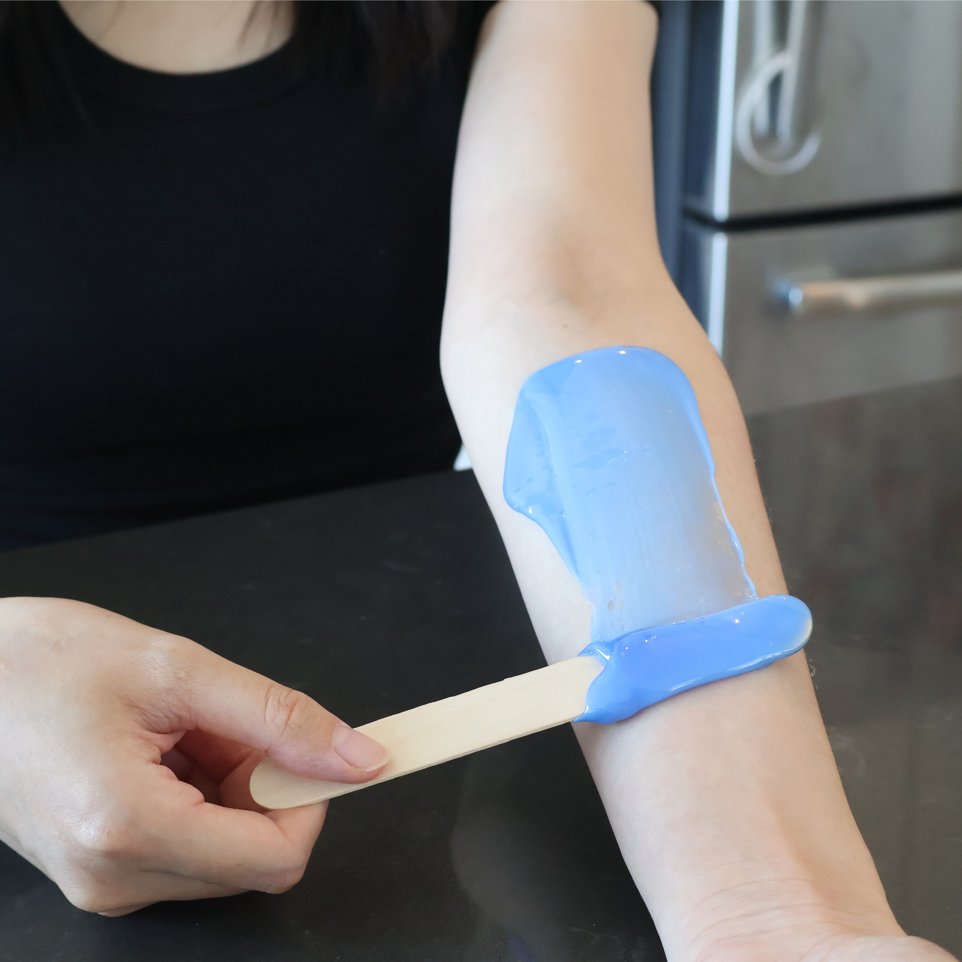 Spreading Lumixsilva hard wax on arm using spatula during at-home hair removal